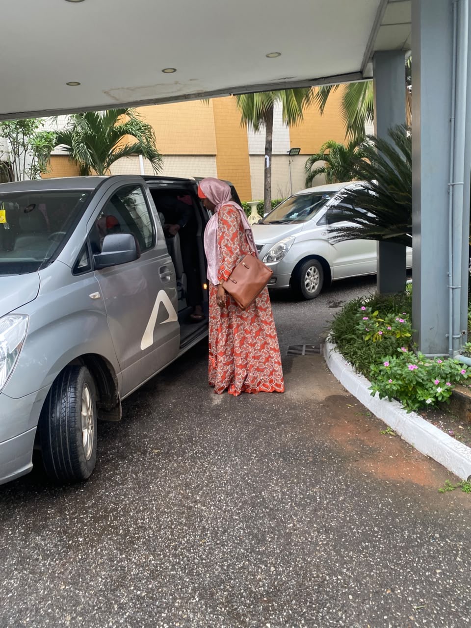 Guest boarding an Allons van under a hotel canopy in Accra